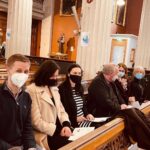 Graphic of a congregation with most people wearing facemasks looking towards the camera and some are continuing to pray with one woman bending her head to pray.