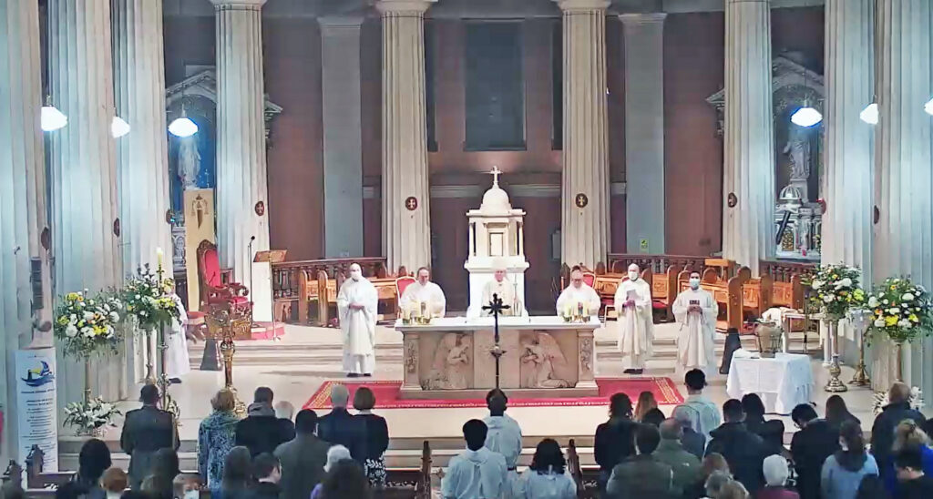 Easter Vigil homily of Archbishop Dermot Farrell. Graphic depicts an altar in a church where five priests are addressing the congregation surrounded by flowers and marble statues.