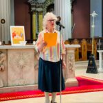 Graphic of a woman holding a piece of paper and reading to the congregation through a microphone.