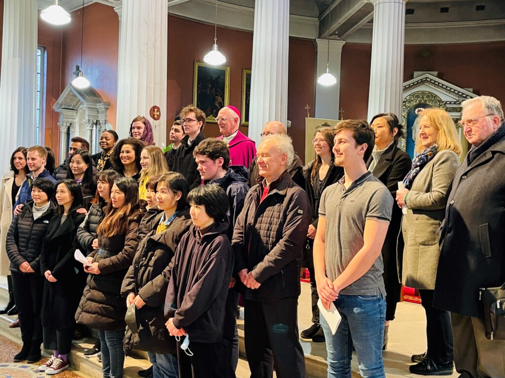 Graphic of a group of people getting their photo taken and smiling towards the other camera with some holding pieces of paper. They are all standing at the altar to get their photo taken.
