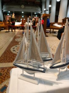 Graphic showing a display of three boats for the Opening Liturgy for the Diocesan Synodal Pathway on a table inside of a church.