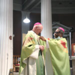 Graphic of His Excellency Archbishop Jude Thaddeus Okolo, Apostolic Nuncio to Ireland placing a religious symbol onto Archbishop Farrell's gown at the altar.