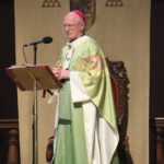 Graphic of Archbishop Farrell speaking to the congregation through a microphone on the stand.