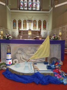Synod display with a model boat, lighthouse, shells and images of animals on blue fabric.