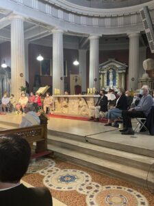Graphic for the Opening Liturgy for the Diocesan Synodal Pathway. Graphic shows a group of people sitting on an altar looking down at the congregation.