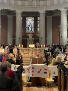 Graphic of a group of people gathered in a Synodal church with a white piece of fabric in the middle of the photo.