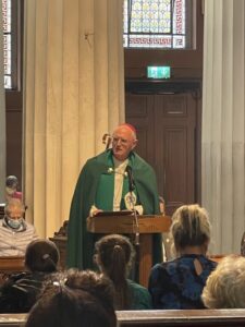 Graphic of Archbishop Farrell in his green and white robe addressing the congregation.