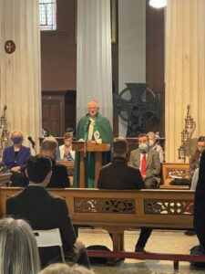 Graphic of Archbishop Farrell in his green and white robe addressing the congregation.