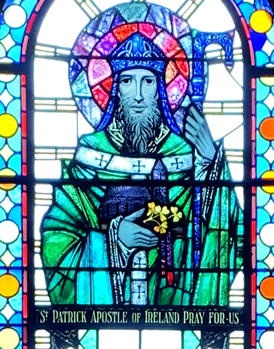 Graphic of a stained glass window's depiction of Saint Patrick who is wearing his traditional green robe and holding the three leaf clover.