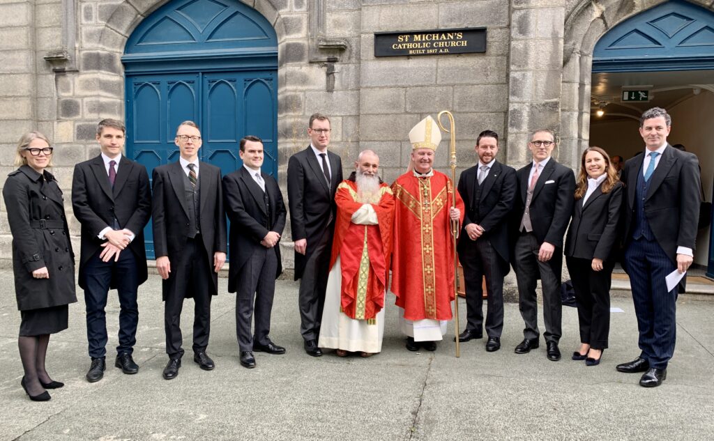 Votive Mass of the Holy Spirit for the Commencement of the New Legal Year, St Michan’s Church, Halston Street, Dublin. Graphic shows Bishop Dempsey with another bishop in red robes standing to get their photos taken with a group of men and women in black attire in front of the Catholic Church. All of the people are smiling at the camera. Monday, October 7, 2024