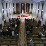 Graphic of a birds eye view of a congregation attending mass in a cathedral with white columns and a priest at the altar.
