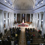 Graphic of a congregation attending mass in a cathedral with white columns and a priest at the altar.