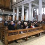 Graphic of the congregation kneeling to pray with most people wearing face masks.