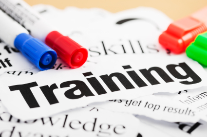 Graphic of pieces of paper with words in a pile with the word training in bold black lettering and two whiteboard markers of red and blue to the left and two highlighters of red and green to the right.