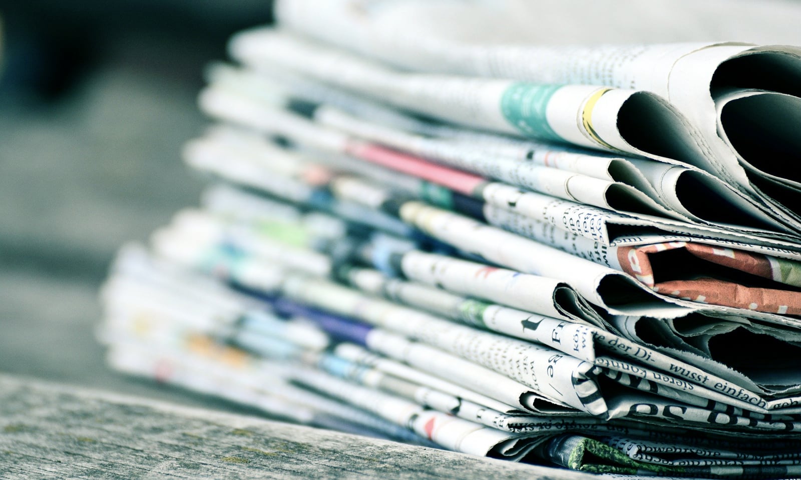 Graphic of a stack of newspapers on a piece of wood.